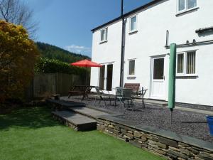 a patio with a table and chairs and an umbrella at Hendre Wen holiday cottage in Betws-y-coed
