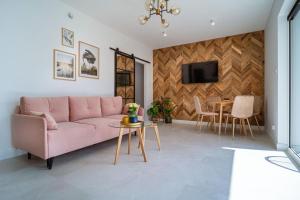 ein Wohnzimmer mit einem rosa Sofa und einem Tisch in der Unterkunft Apartament J&T Mrągowo in Mrągowo