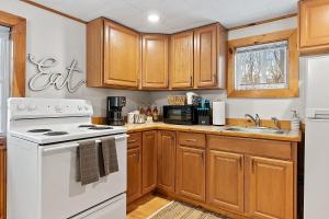 a kitchen with wooden cabinets and a white stove top oven at Mountainscape Cabins 1 in Thornton +8 photos