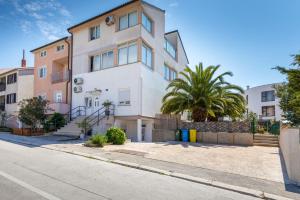 a white building with a palm tree in front of it at Apartman Mia in Pula