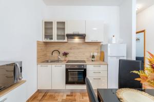 a kitchen with white cabinets and a sink and a refrigerator at Apartman Mia in Pula