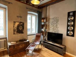 - un salon avec une télévision et une chaise dans l'établissement Santorio 5 Apartment, à Trieste