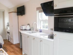 a white kitchen with a sink and a microwave at The Folly in Skipton