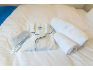 um roupão branco e toalhas numa cama em HOTEL LANTANA Naha Kokusai Street - Vacation STAY 65213v em Naha
