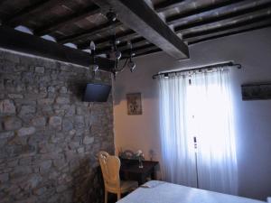 a bedroom with a stone wall and a table and a window at Casa Shalom in Pennabilli