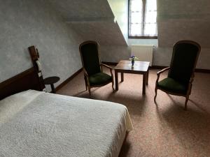 a bedroom with a bed and two chairs and a table at Relais des Ardides in Bonnemazon