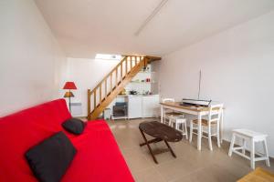 Sala de estar con cama roja y mesa en Petite maison bourg de La Trinite sur Mer - 4 à 6 couchages, en La Trinité-sur-Mer