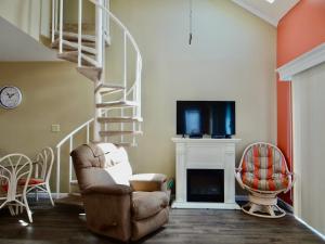 a living room with a staircase and a chair and a television at Coral Cottage-3B GCR in Myrtle Beach