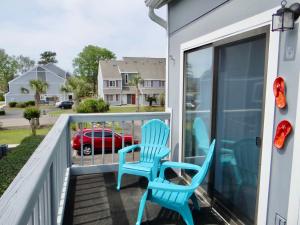 une paire de chaises bleues assises sur la terrasse couverte d'une maison dans l'établissement Coral Cottage-3B GCR, à Myrtle Beach