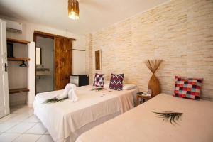 Habitación con 2 camas y pared de ladrillo en Pousada do Mel, en Arraial d'Ajuda