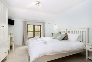 a white bedroom with a white bed and a window at The Coach House at The Old Rectory in Stoke Prior
