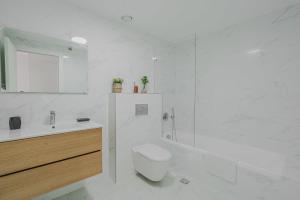La salle de bains blanche est pourvue de toilettes et d'un lavabo. dans l'établissement Charming 1BR Agripas Jerusalem By Holiday Rentals, à Jérusalem
