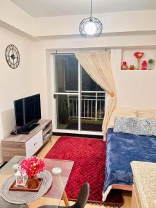 a living room with a bed and a large window at 1 BR Condo Unit at The Celandine Condominium near Ayala Cloverleaf Mall in Manila