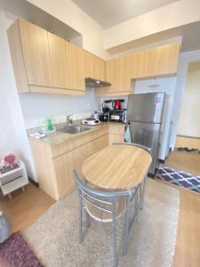 a kitchen with a wooden table and a stainless steel refrigerator at 1 BR Condo Unit at The Celandine Condominium near Ayala Cloverleaf Mall in Manila