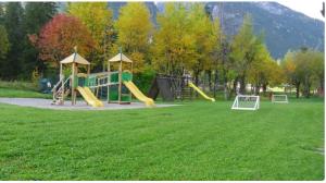 un parque infantil con un tobogán en un campo de césped en Mansarda Élite Villaggio Ploner, en Dobbiaco