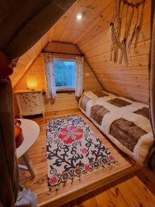 a bedroom in a log cabin with a bed and a rug at Wiejska Chata in Barczewo