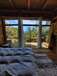 a bedroom with a large bed and a large window at Yahoo ecolodge in Bocaina do Sul