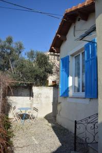 een tafel en stoelen buiten een huis met blauwe luiken bij Petite maison bord et vue mer, 55 m2 in Martigues