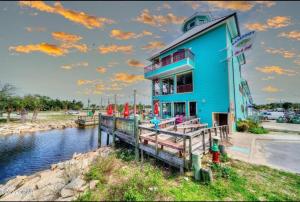 a blue building next to a body of water at Historic GWALTNEY HOUSE-Cottage at St Andrew's Bay in Panama City