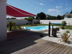 a swimming pool in a yard with a red umbrella at Villa Oyala avec piscine, spacieuse et de qualite in Saint-Pierre-dʼOléron
