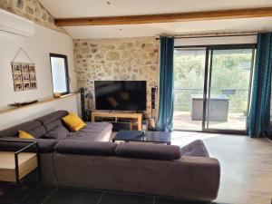 ein Wohnzimmer mit einem braunen Sofa und einem TV in der Unterkunft Chaleureuse bergerie rénovée. in Tourrette-Levens