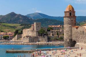 a group of people on a beach next to a castle at Duplex terrasse, Collioure in Collioure