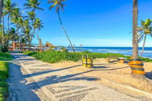 a sandy beach with palm trees and the ocean at Casa com piscina e churrasq em Lauro de Freitas BA in Lauro de Freitas