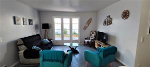 a living room with a couch and chairs and a tv at Villa Ohana proche centre-ville in Le Château-dʼOléron
