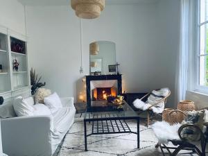 a living room with a fireplace and white furniture at Villa Constantine a 2 pas du port de Boyardville in Saint-Georges-dʼOléron