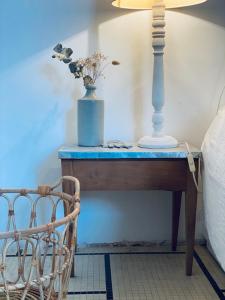 a table with a lamp and a vase of flowers on it at Villa Constantine a 2 pas du port de Boyardville in Saint-Georges-dʼOléron