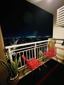 Duas cadeiras vermelhas numa varanda com vista em 1 BR Condo Unit at The Celandine Condominium near Ayala Cloverleaf Mall em Manila