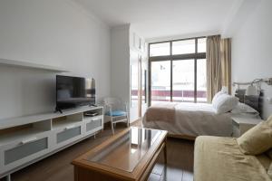 1 dormitorio con 1 cama, TV y sofá en Estudio con vistas al mar en Las Canteras, en Las Palmas de Gran Canaria