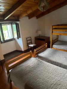 a bedroom with two bunk beds and a chair at Albergue Rectoral de Romean in Lugo