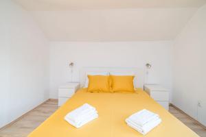 a yellow bed with two yellow pillows on it at Magnolia Apartments, Dubrovnik in Dubrovnik