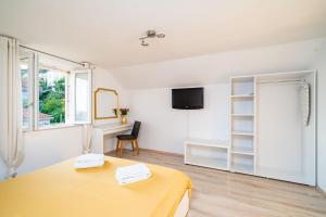 a white room with a yellow table and a desk at Magnolia Apartments, Dubrovnik in Dubrovnik
