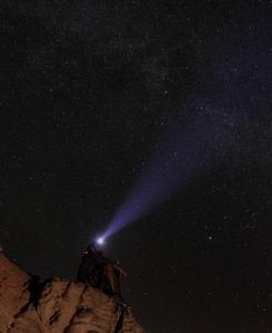 une personne debout au sommet d'une montagne la nuit dans l'établissement Wadi Rum Meteorite camp, à Wadi Rum