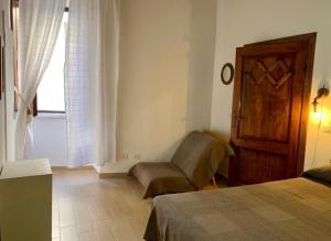 1 dormitorio con 1 cama, 1 silla y 1 ventana en Ànita holiday house, en Montemerano
