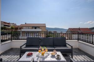 a couch on a balcony with food on a table at Villa Barbara & Zoran with heated swimming pool in Seget Vranjica