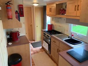 a kitchen with wooden cabinets and a stove top oven at 6 Berth Caravan on Sealands Site. Double Glazing in Ingoldmells