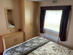 a small bedroom with a bed and a window at 6 Berth Caravan on Sealands Site. Double Glazing in Ingoldmells