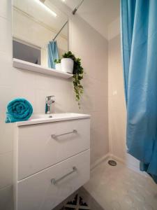 a white bathroom with a sink and a blue shower curtain at Appartement tout équipé terrasse parking privatif in Six-Fours-les-Plages