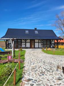 a building with a black roof on top of a field at DERCÓWKA in Mieroszyno