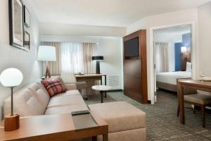Residence Inn by Marriott Tampa at USF/Medical Center في تامبا: غرفة في الفندق مع أريكة وغرفة نوم
