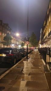 a city street at night with cars parked at Spacious 2 bedroom flat in Baker street in London