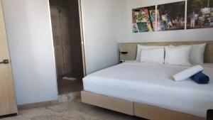 a bedroom with a large white bed and a bathroom at Hotelito del Mar Playa del Carmen in Playa del Carmen
