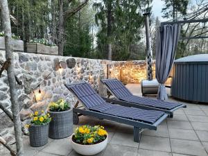 dwa krzesła i kwiaty na patio z kamienną ścianą w obiekcie Mellene 1 bedroom house in nature & hot tube w mieście Turaida