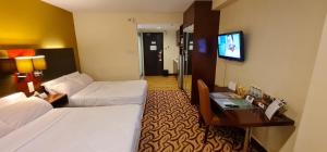 um quarto de hotel com duas camas e uma secretária e uma televisão em BV1 STUDIO KK CITY CENTRE WITH POOL NEAR Imago em Kota Kinabalu