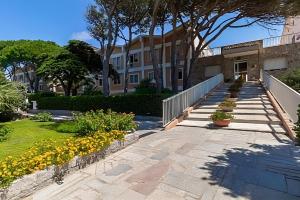 a walkway leading to a building with trees and flowers at Appartamento La Terrazza al Gallo di Gallura in Santa Teresa Gallura