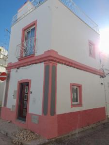 Un edificio blanco y rojo con un balcón. en Casa Rosa, en Olhão