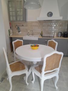 uma mesa branca e cadeiras numa cozinha em Casa Rosa em Olhão